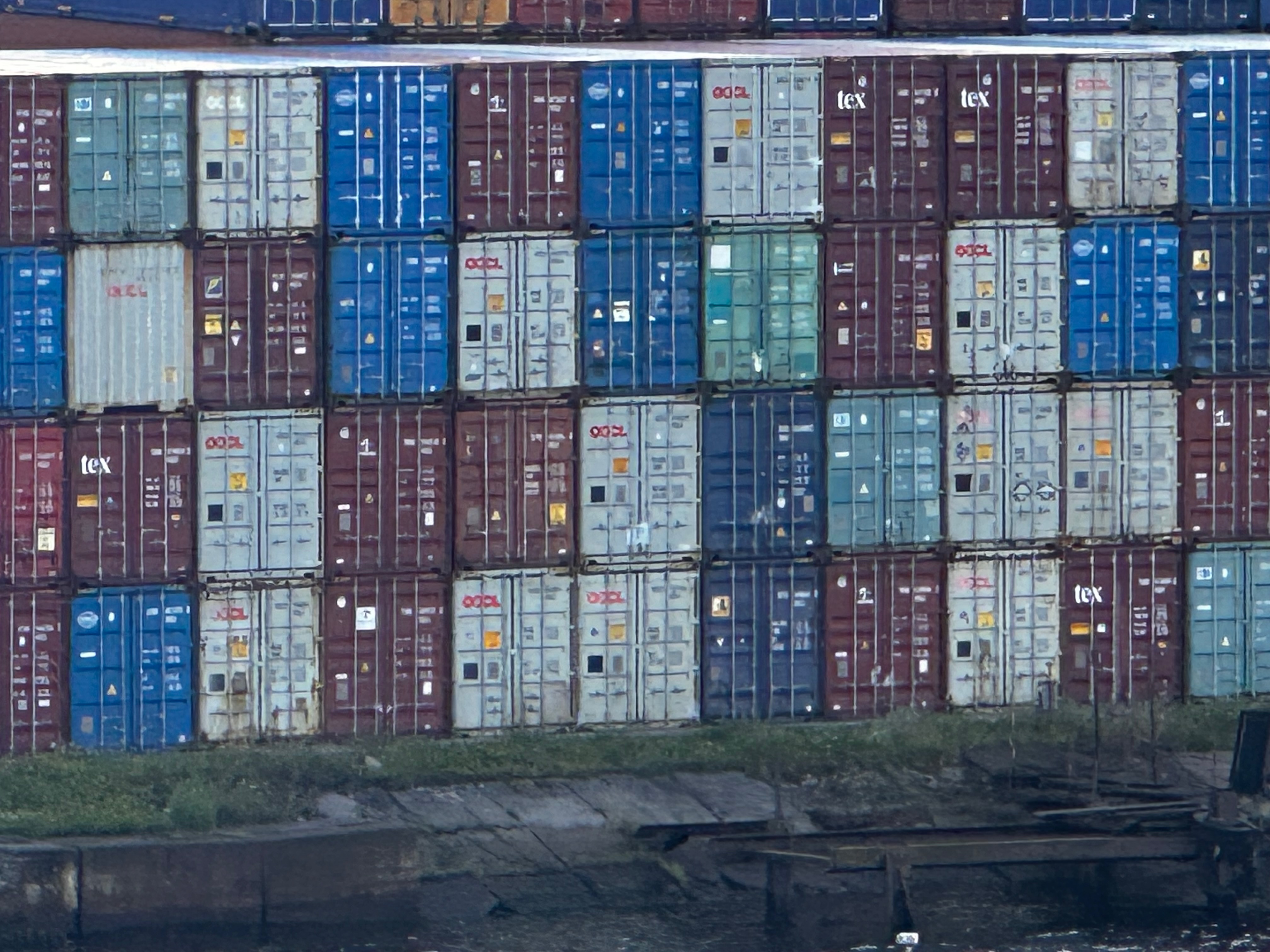 Multiple shipping containers stacked on a pier.